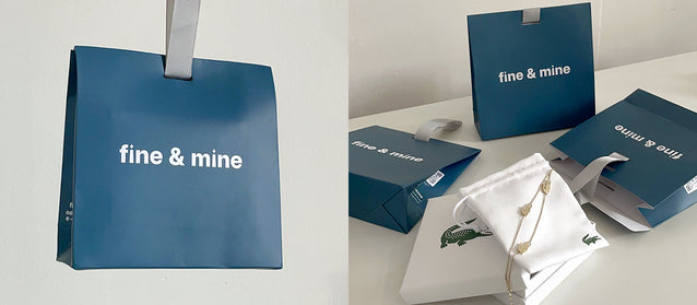 Blue 'fine & mine' bags and jewelry packaging on a white surface